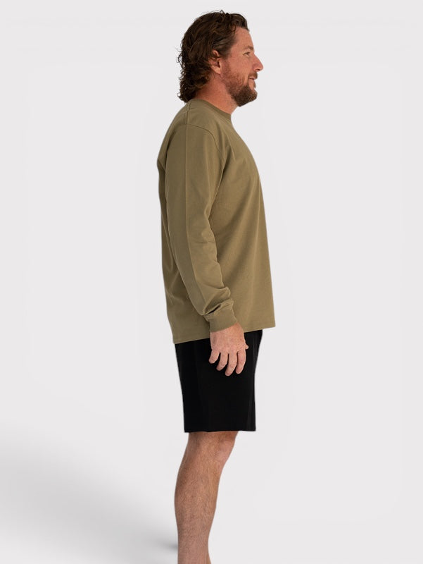 Man wearing a khaki long-sleeve shirt and black shorts on a white background