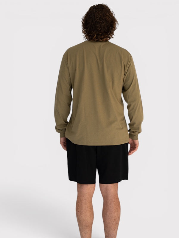 Person wearing a long-sleeve olive green shirt and black shorts on a white background