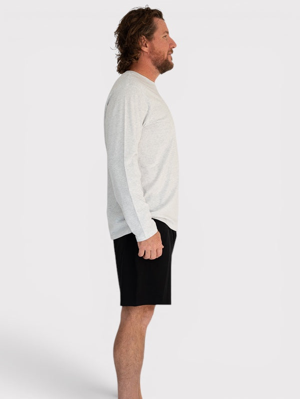 Man wearing a light grey sweater and black shorts on a white background