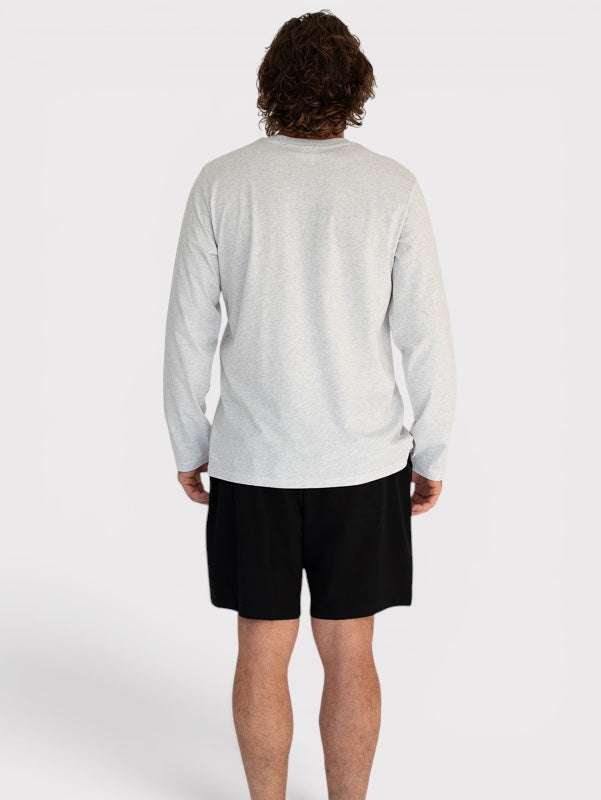 Person wearing a light grey long-sleeve shirt and black shorts on a white background