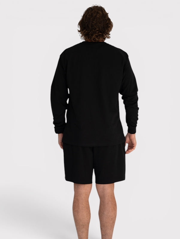 Person wearing a black long-sleeve shirt and shorts on a white background