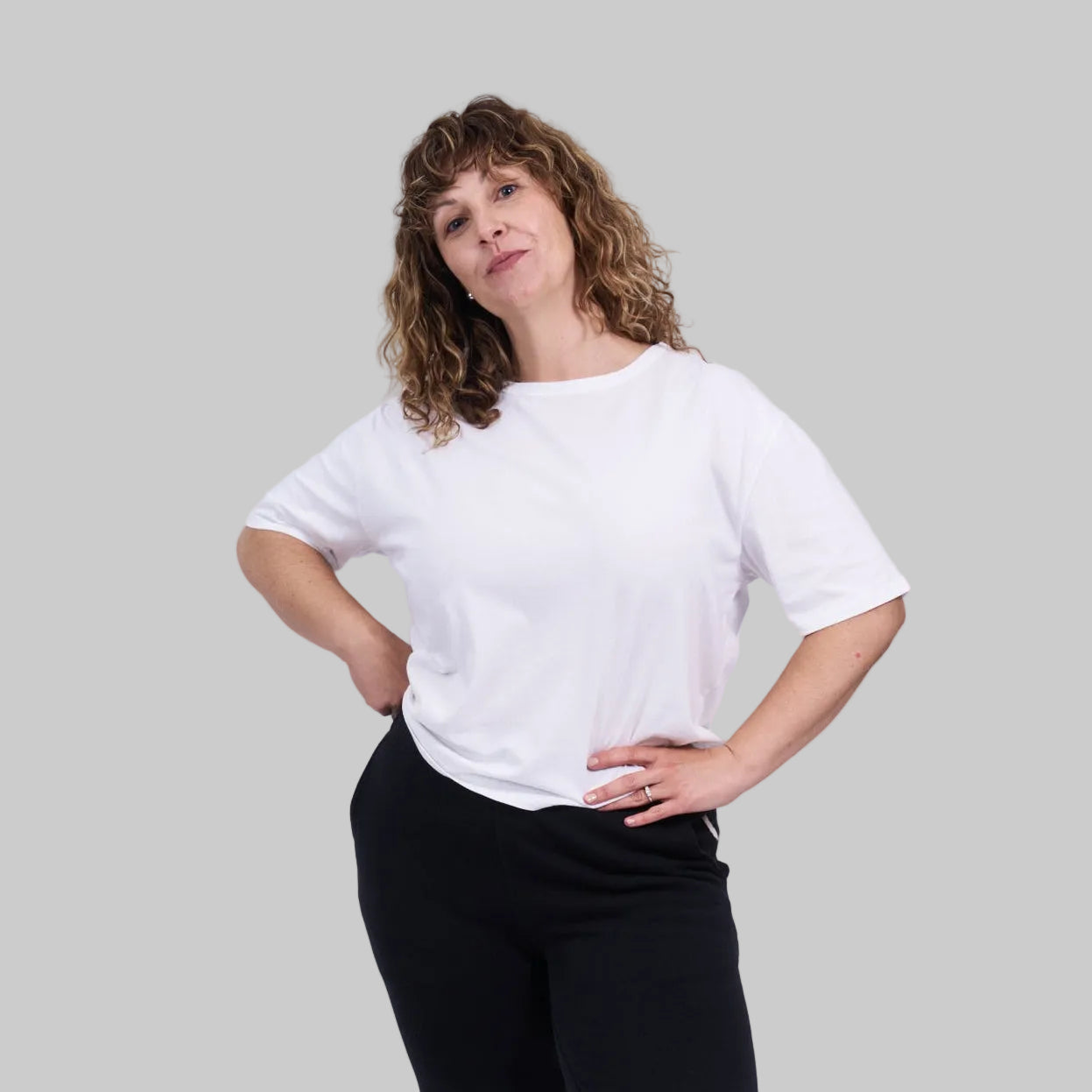 Person wearing a white t-shirt and black pants on a light gray background