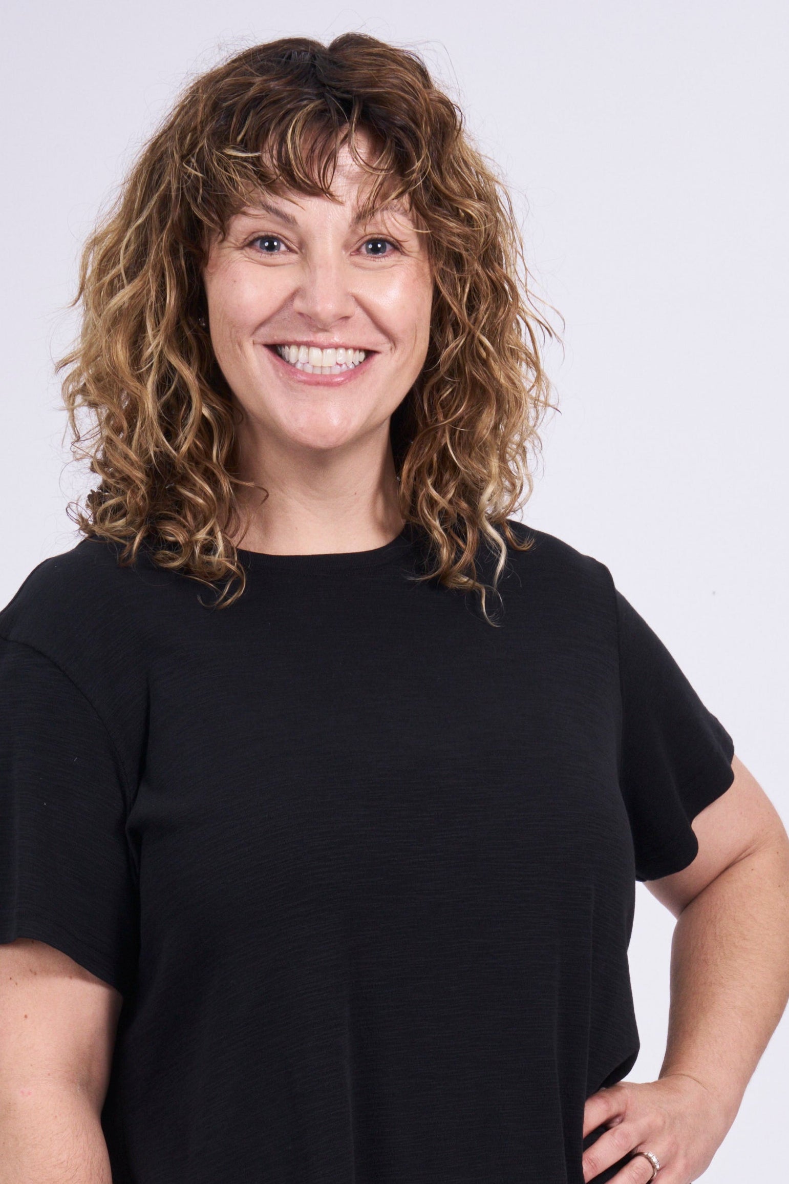 Person wearing a black t-shirt and beige shorts on a white background