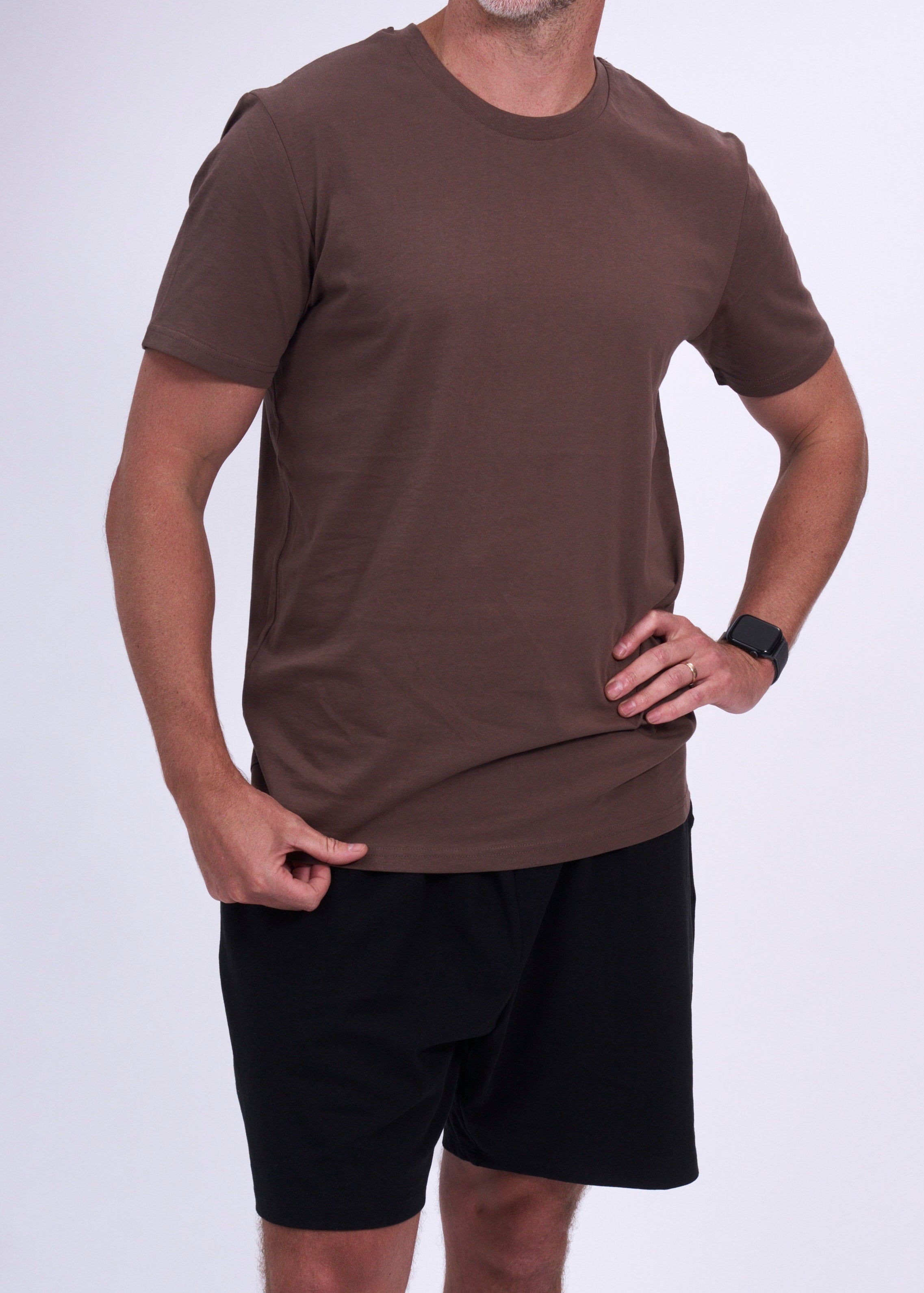 Man wearing a brown t-shirt and black shorts on a white background
