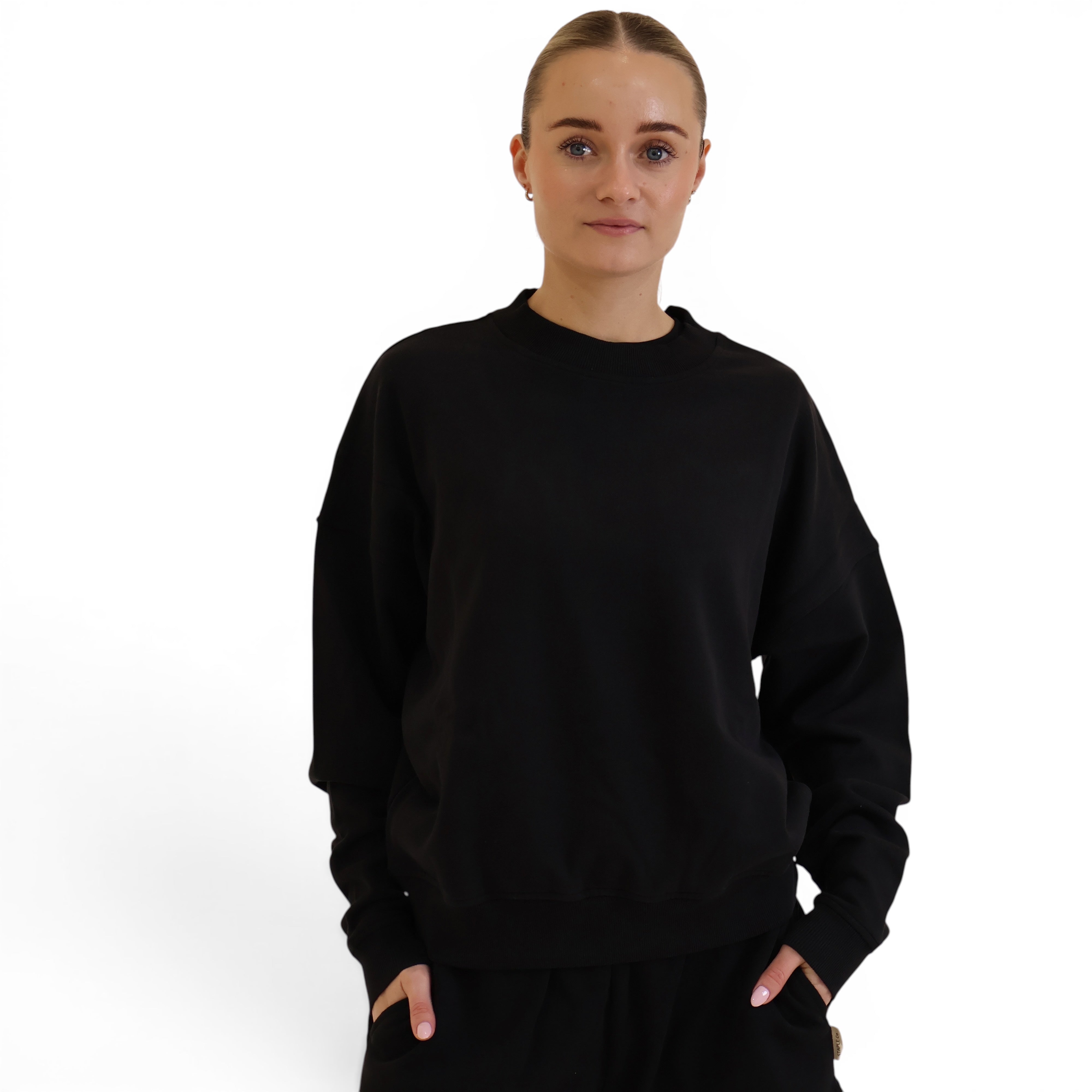 Model wearing a black STAPLE Co oversized crewneck sweater made from soft regenerative organic cotton fleece.