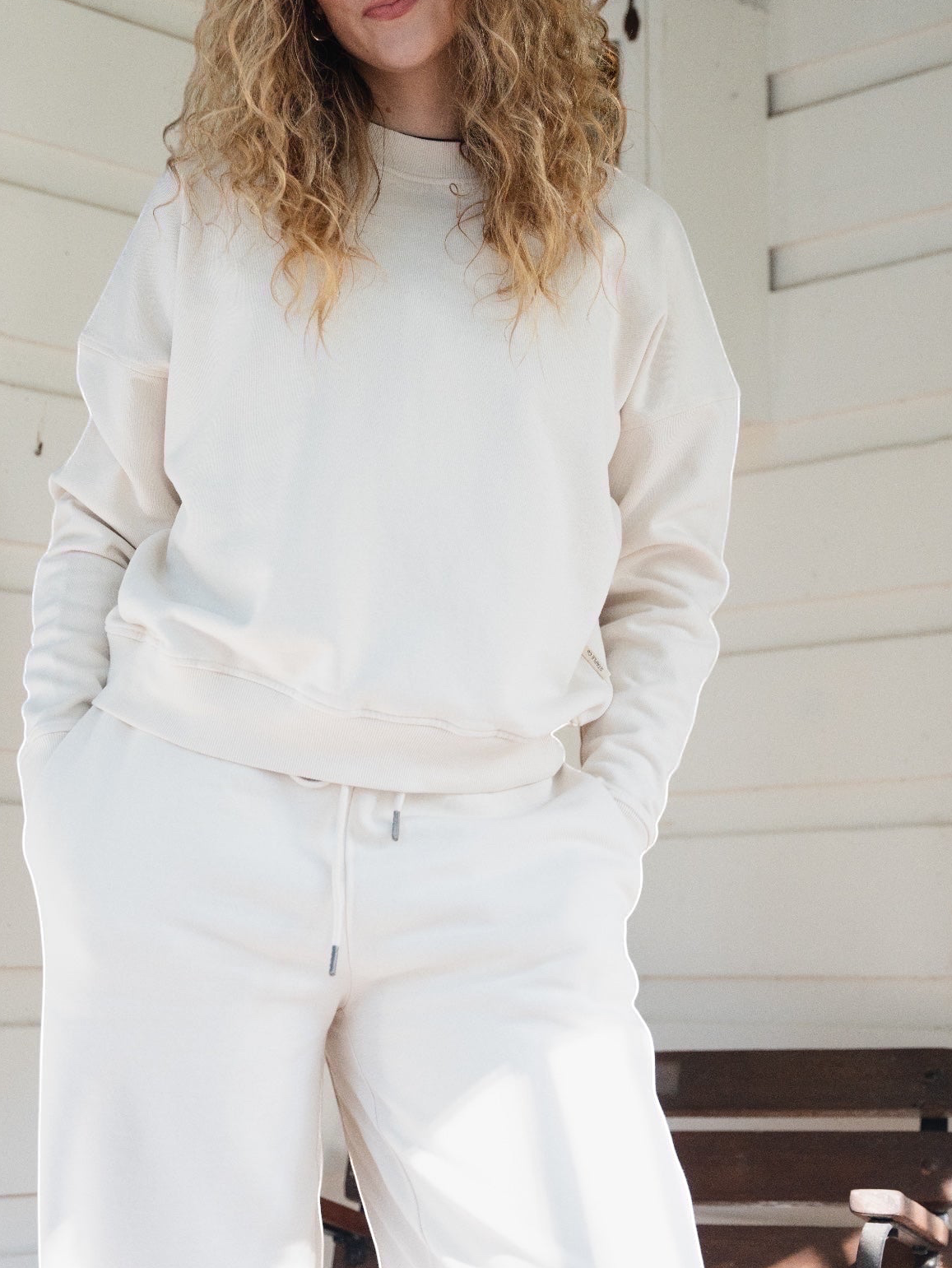 Woman wearing a STAPLE Co boxy cream crewneck pullover made from Regenerative Organic Certified cotton fleece.