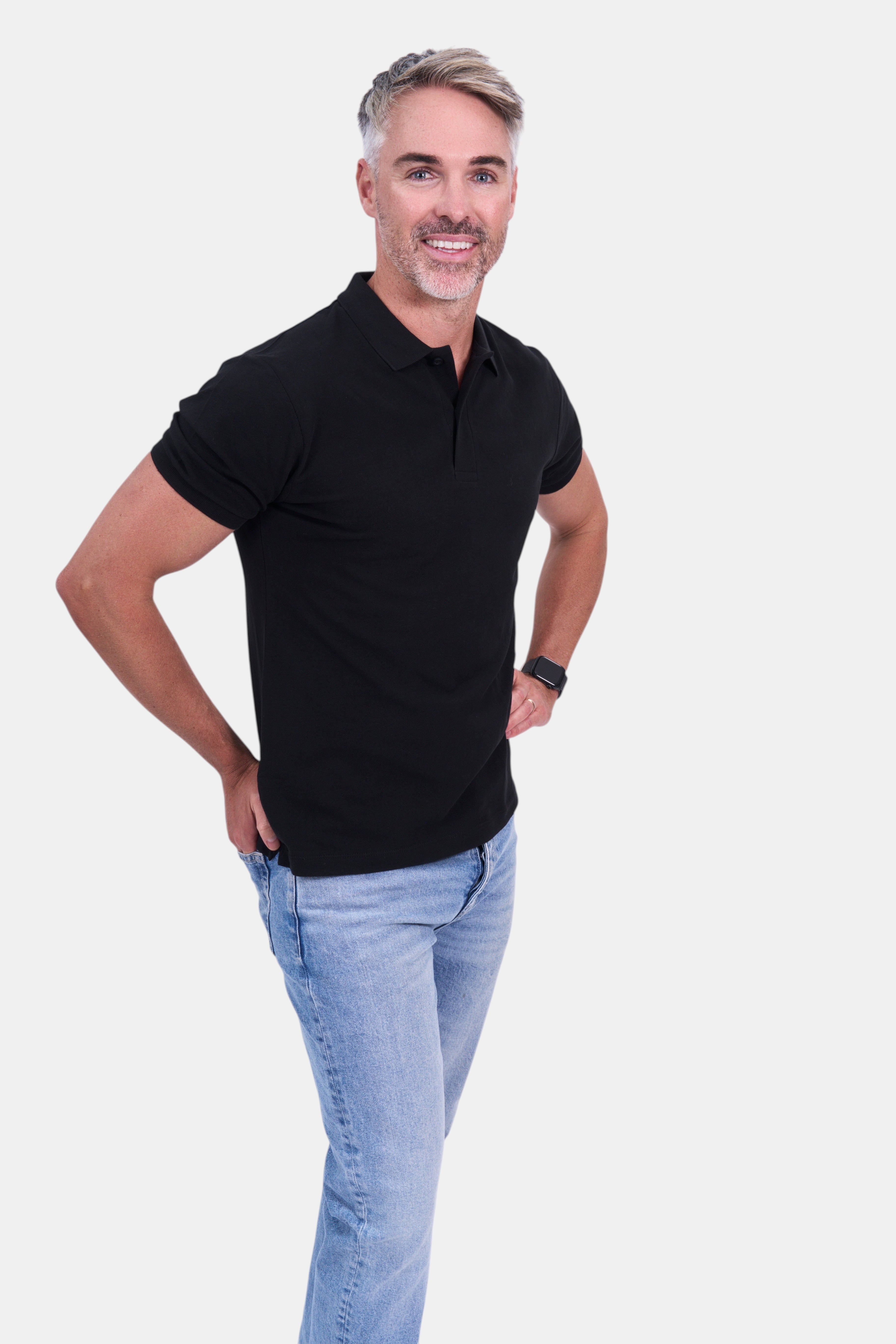 STAPLE Co black organic cotton polo shirt with short sleeves, worn by a man with light blue jeans.