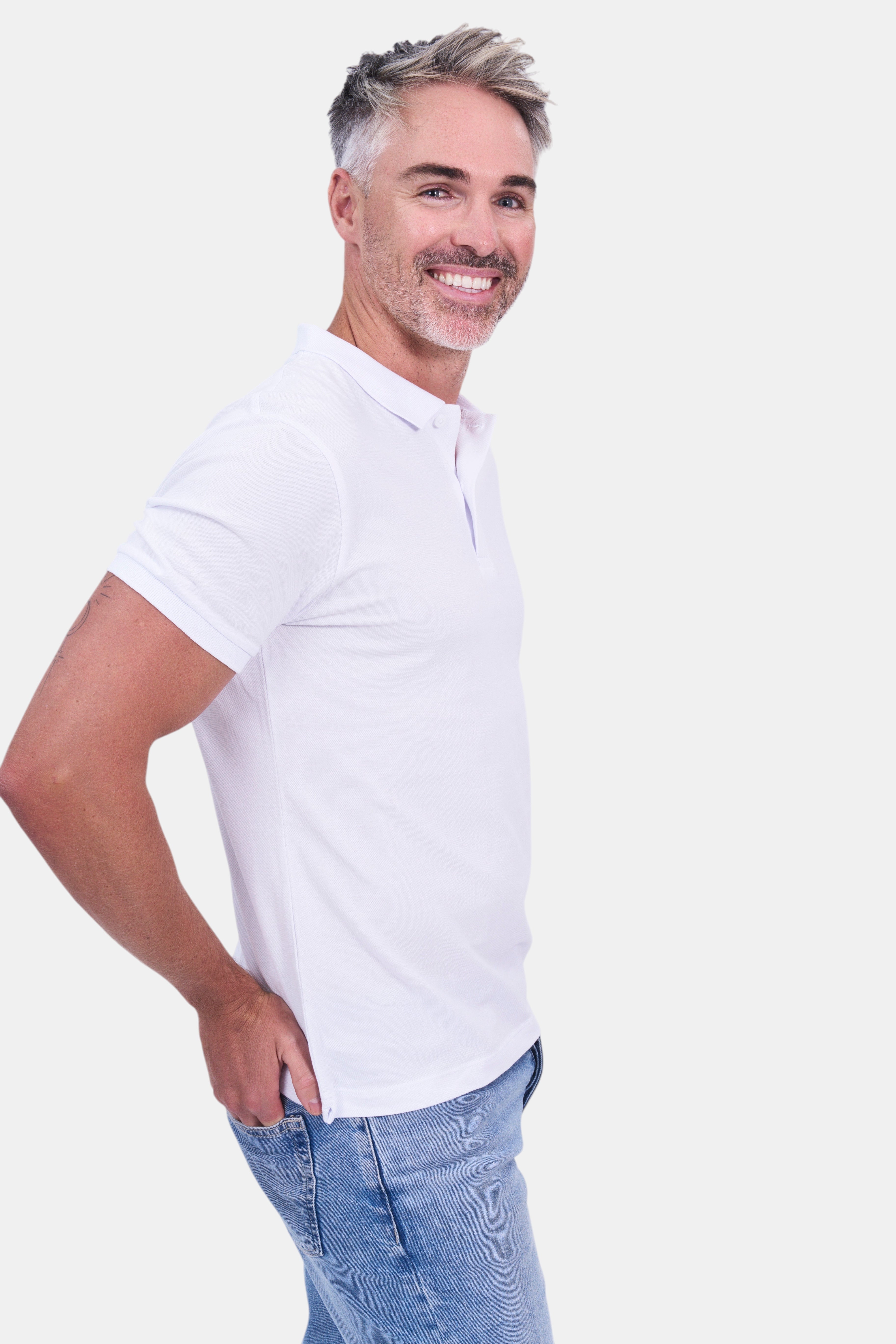STAPLE Co white organic cotton polo shirt on a man with grey hair and blue jeans.