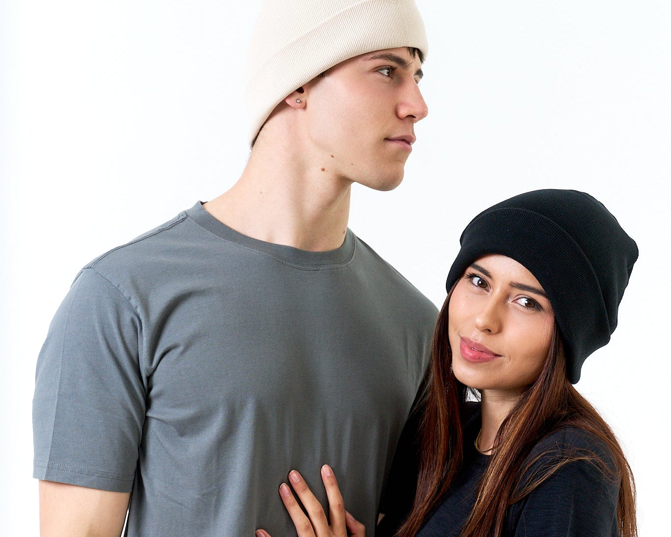 Two people wearing beanies and casual clothing on a white background