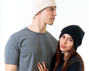 Two people wearing beanies and casual clothing on a white background