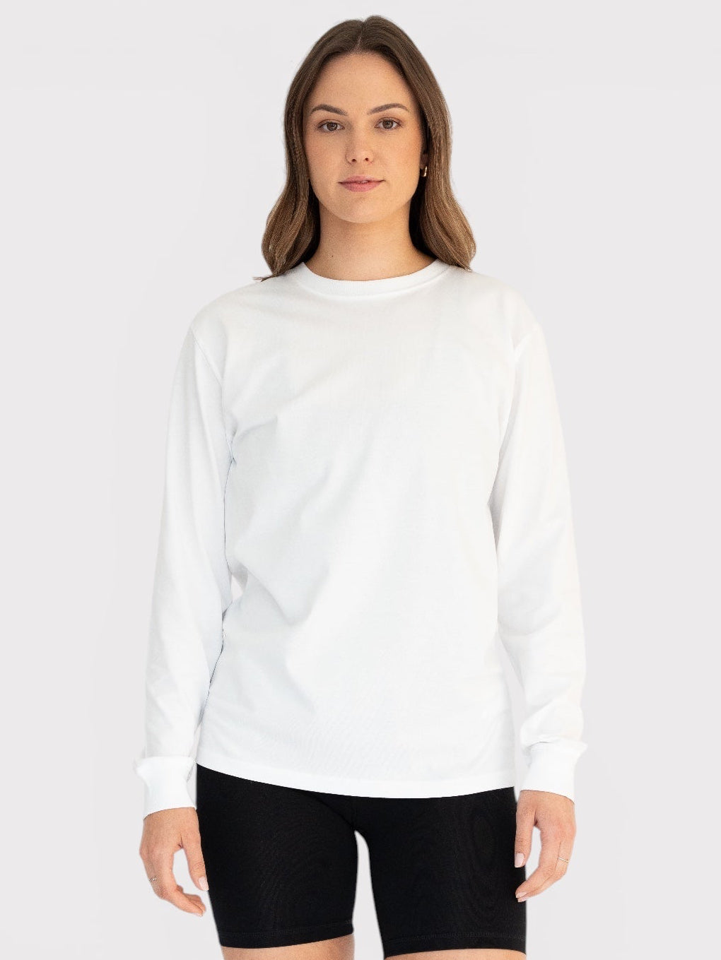 Woman wearing a white long-sleeve shirt and black shorts on a white background