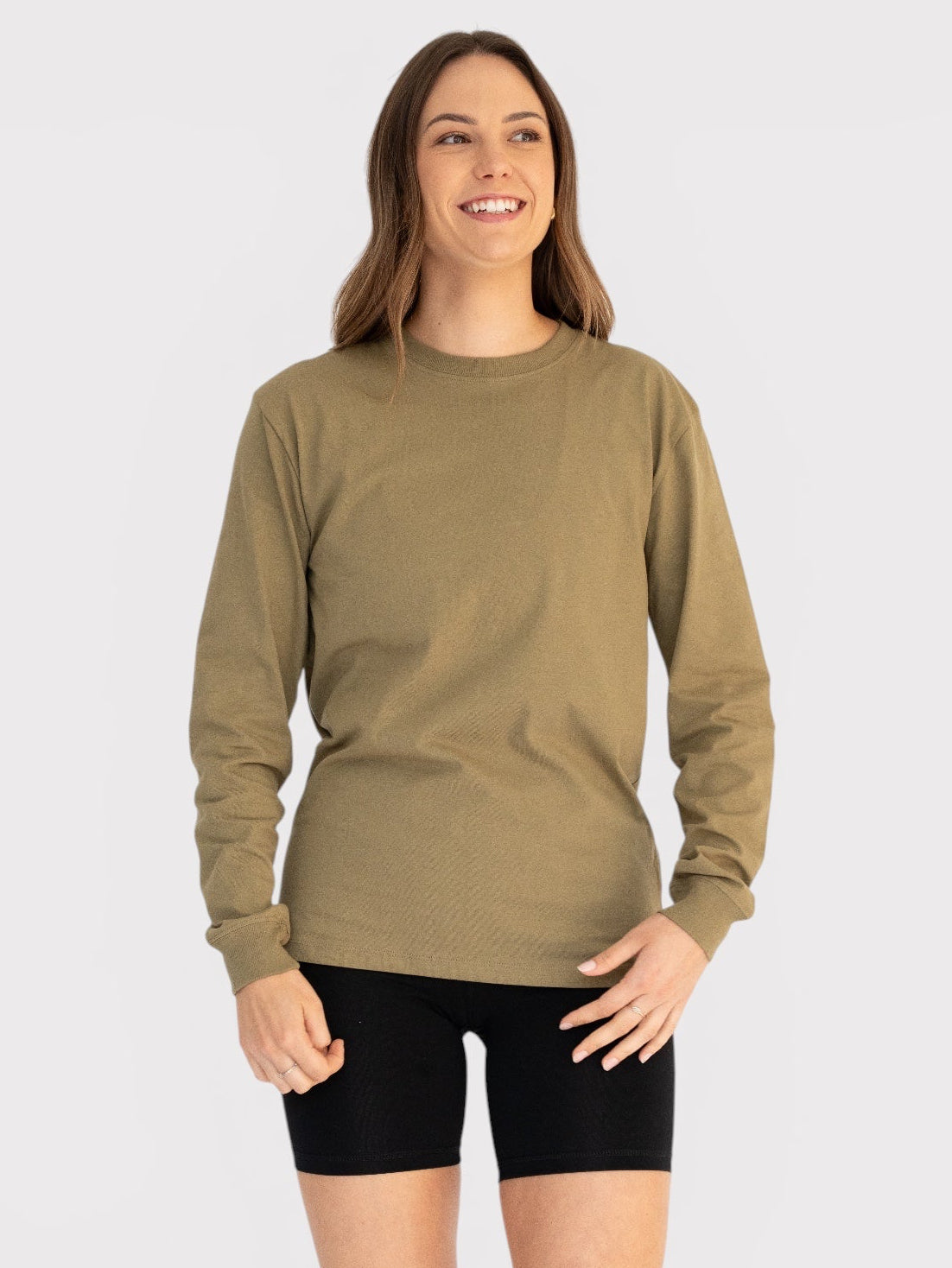Woman wearing a khaki long-sleeve shirt and black shorts on a white background