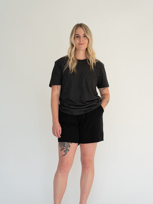 Person wearing a black t-shirt and black shorts on a white background