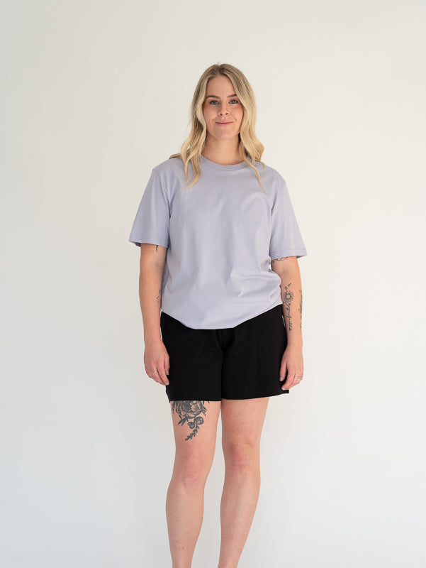 Person wearing a light gray t-shirt and black shorts on a white background
