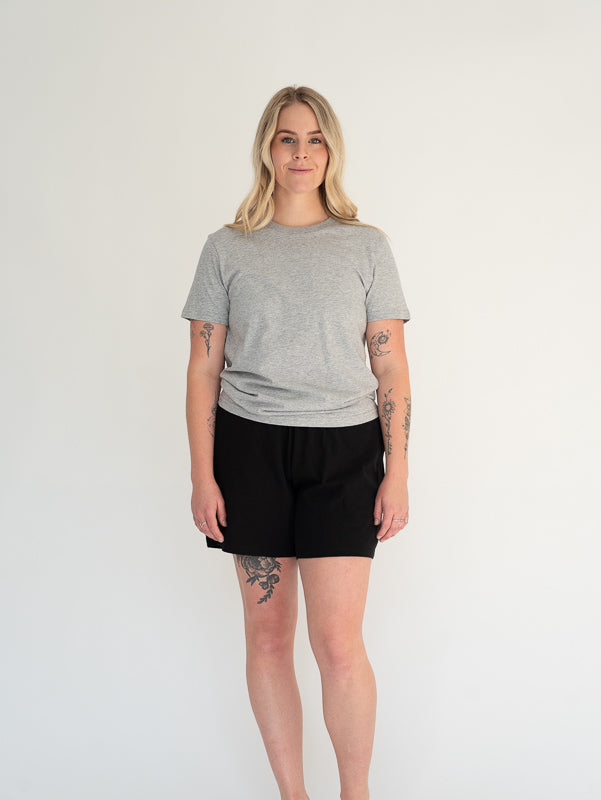 Person wearing a gray t-shirt and black shorts on a white background
