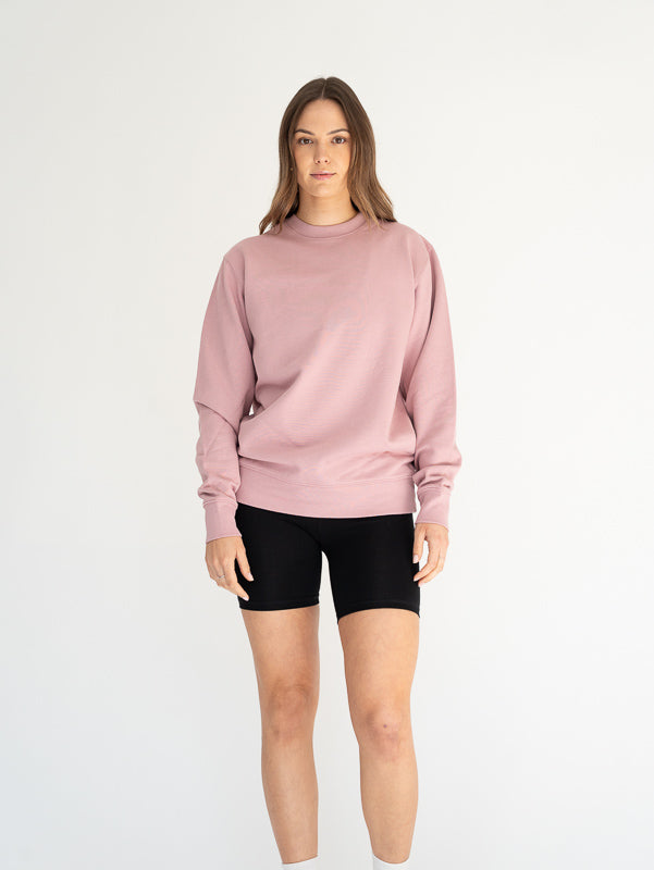 Person wearing a pink sweatshirt and black shorts on a white background