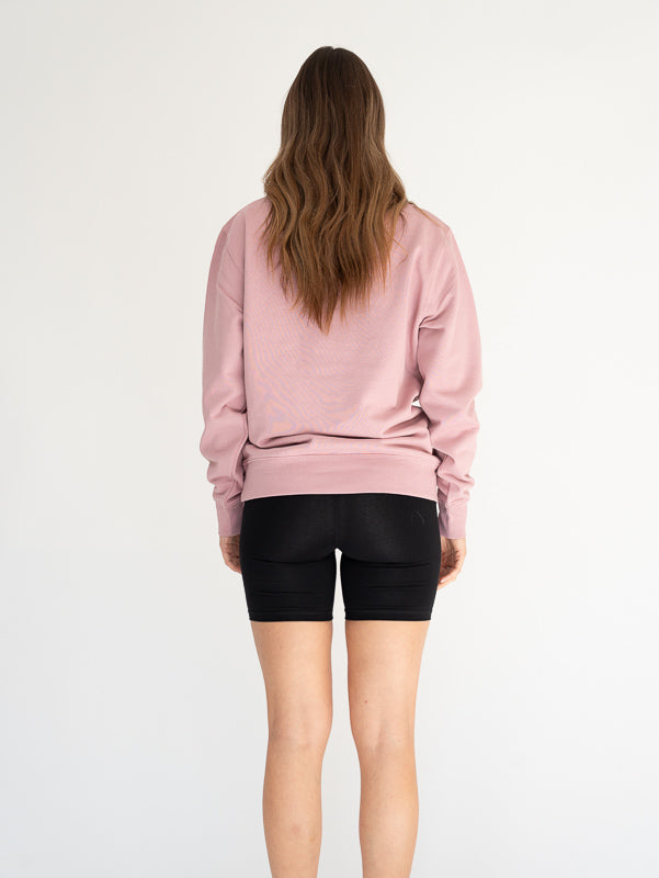 Person wearing a pink sweatshirt and black shorts on a white background