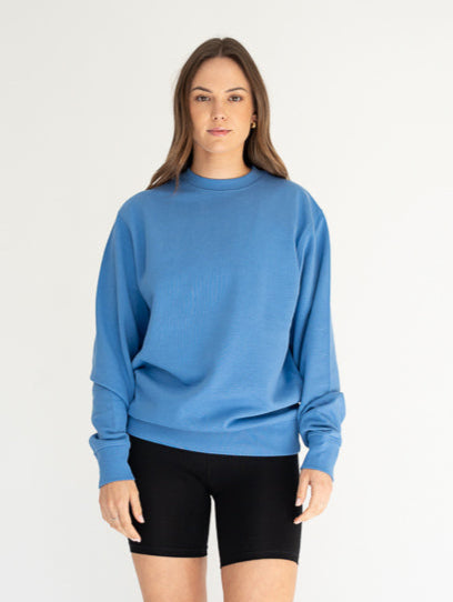 Woman wearing a blue sweater and black shorts on a white background