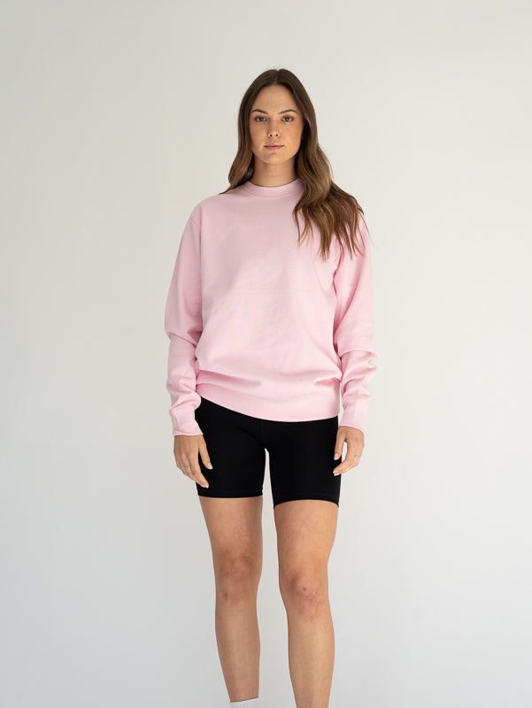 Person wearing a pink sweatshirt and black shorts on a white background