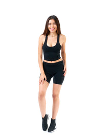 Woman wearing a black tank top and shorts on a white background