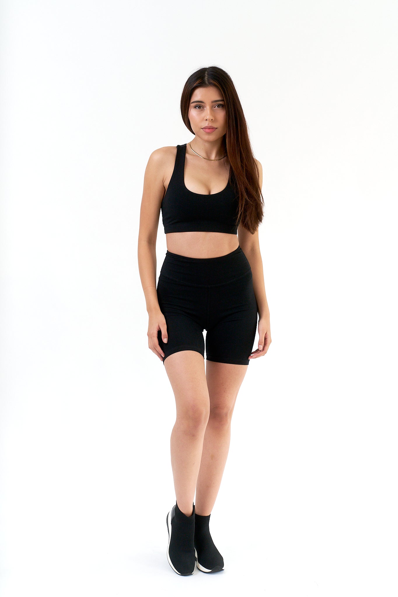 Woman wearing a black sports bra and shorts on a white background