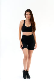 Woman wearing a black sports bra and shorts on a white background