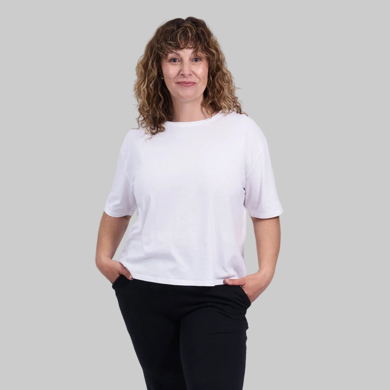 Person wearing a white t-shirt and black pants against a plain background