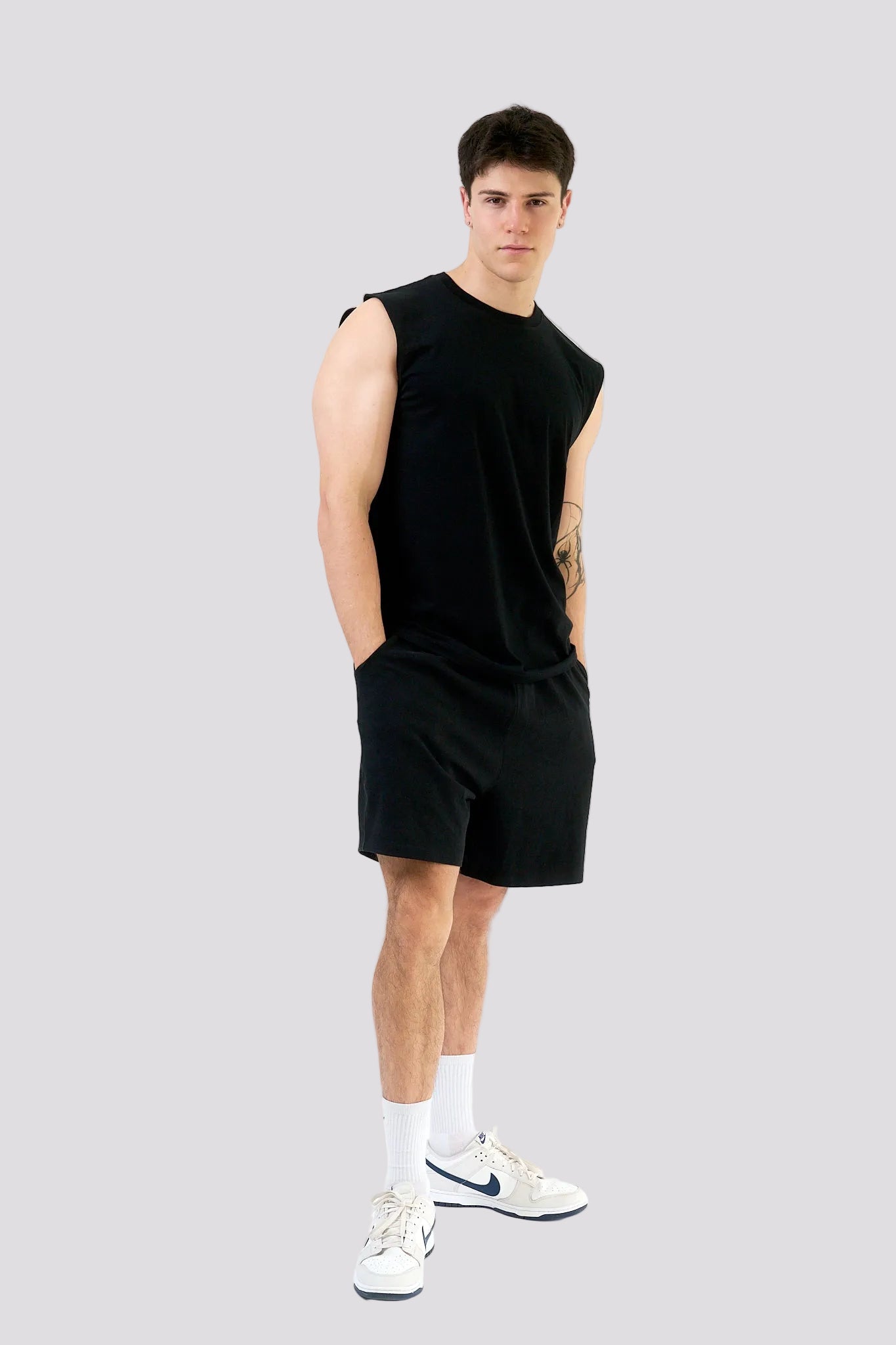 Man wearing a black sleeveless shirt and shorts on a white background