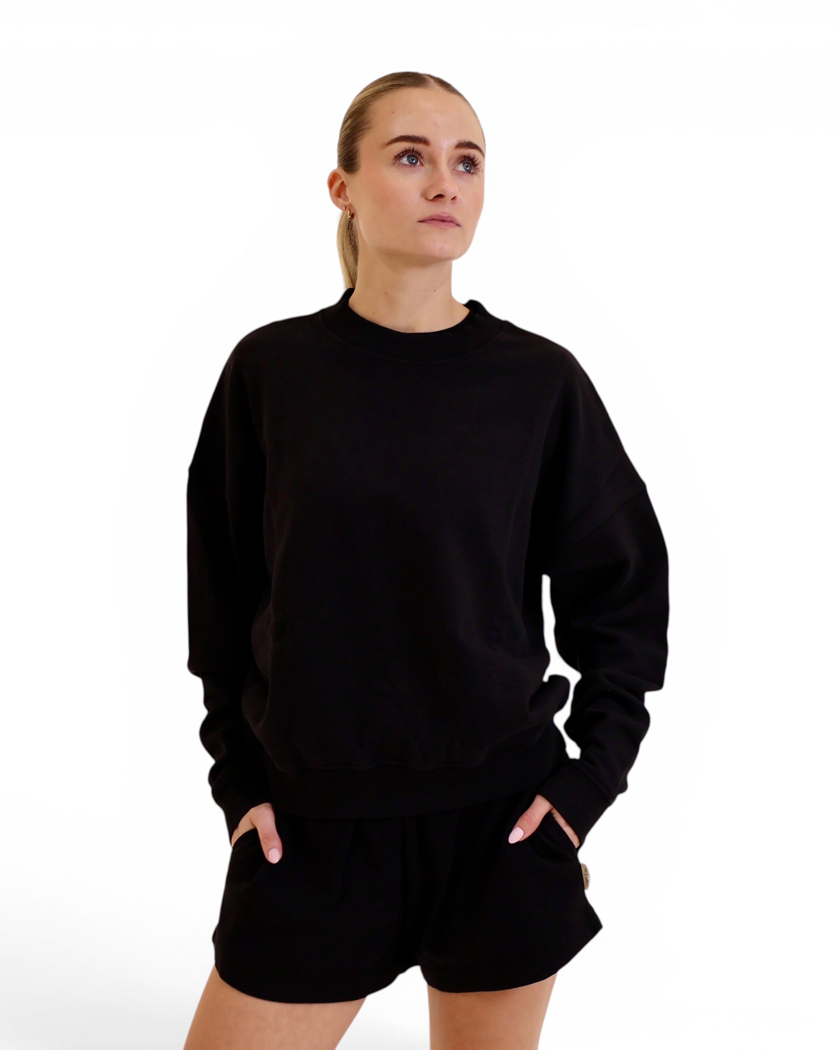 Model wearing a black STAPLE Co oversized crewneck pullover in regenerative organic cotton fleece.