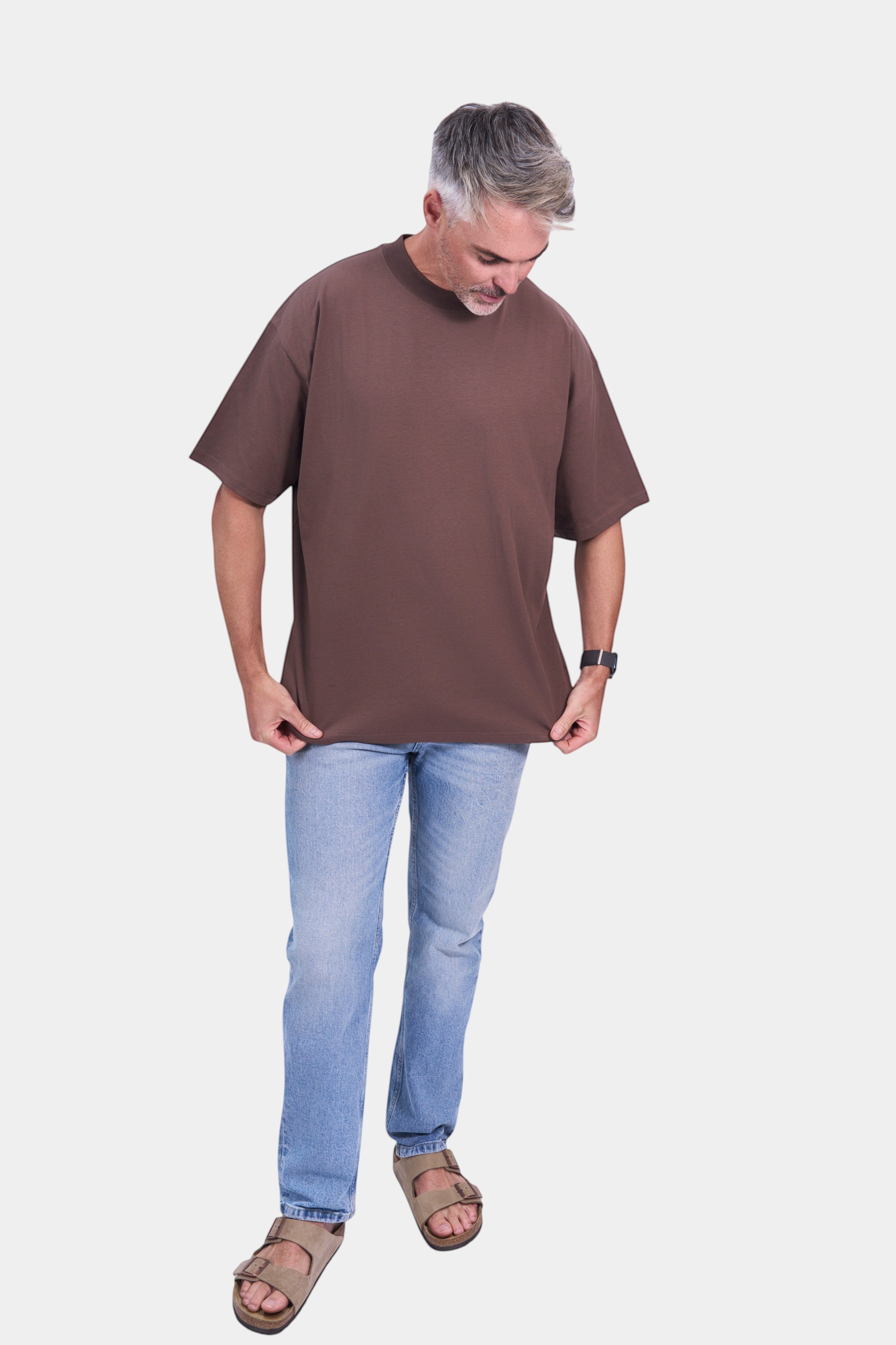 STAPLE Co brown organic cotton high neck oversized t-shirt on a man with light wash jeans and sandals.