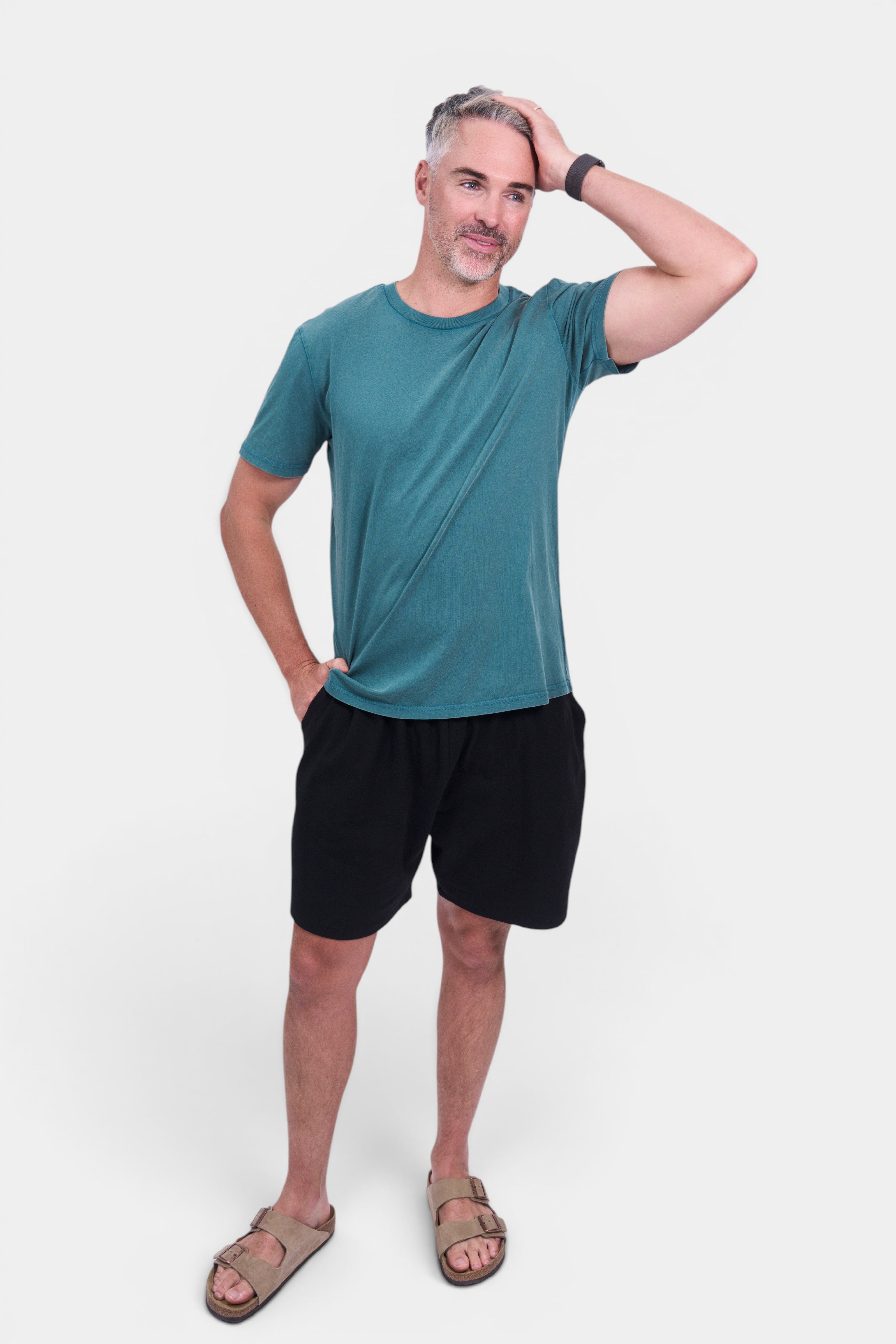 STAPLE Co men's teal organic cotton classic fit tee with black shorts and tan sandals.