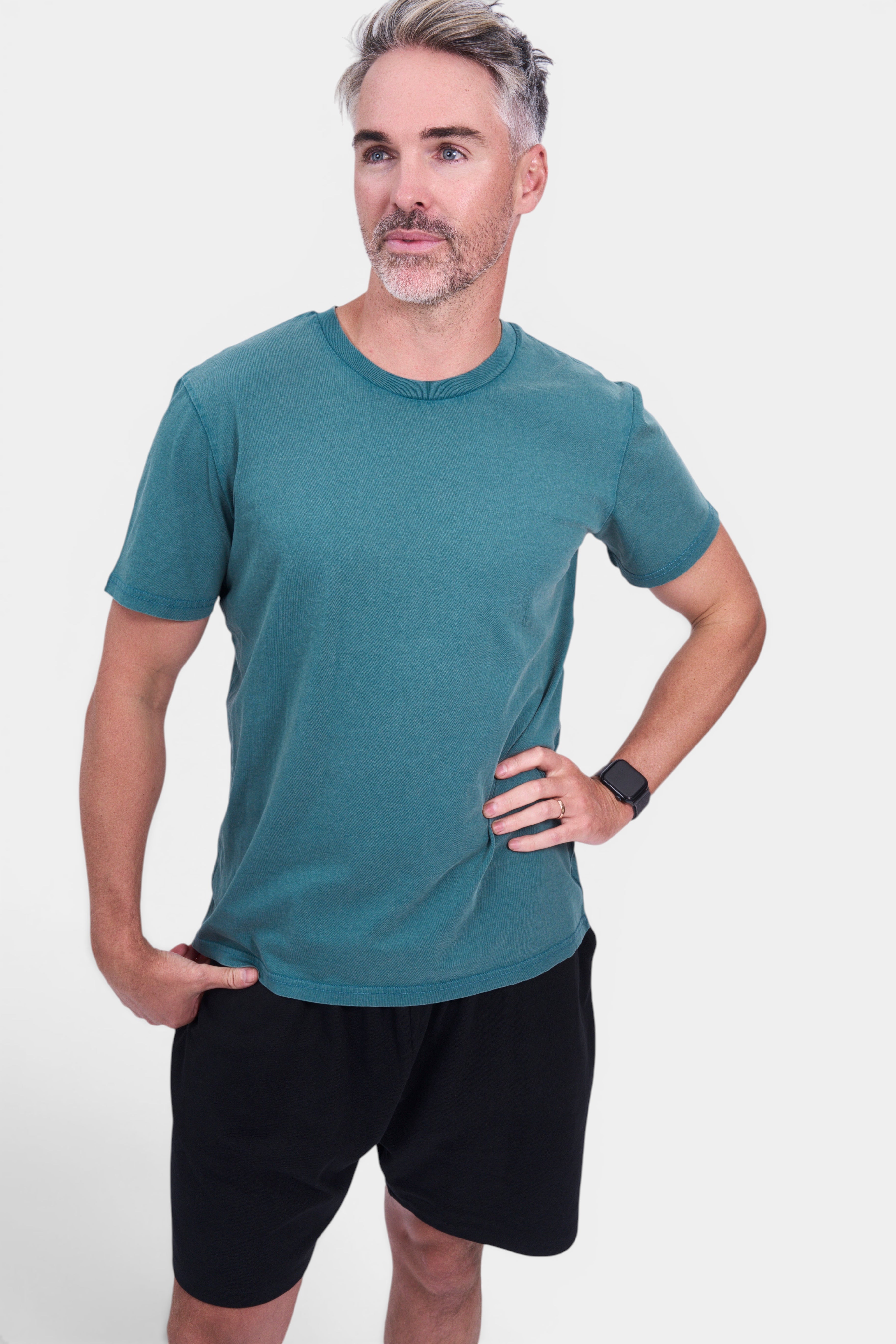 STAPLE Co. teal organic cotton classic fit tee with crew neck and short sleeves, worn by a man with black shorts.