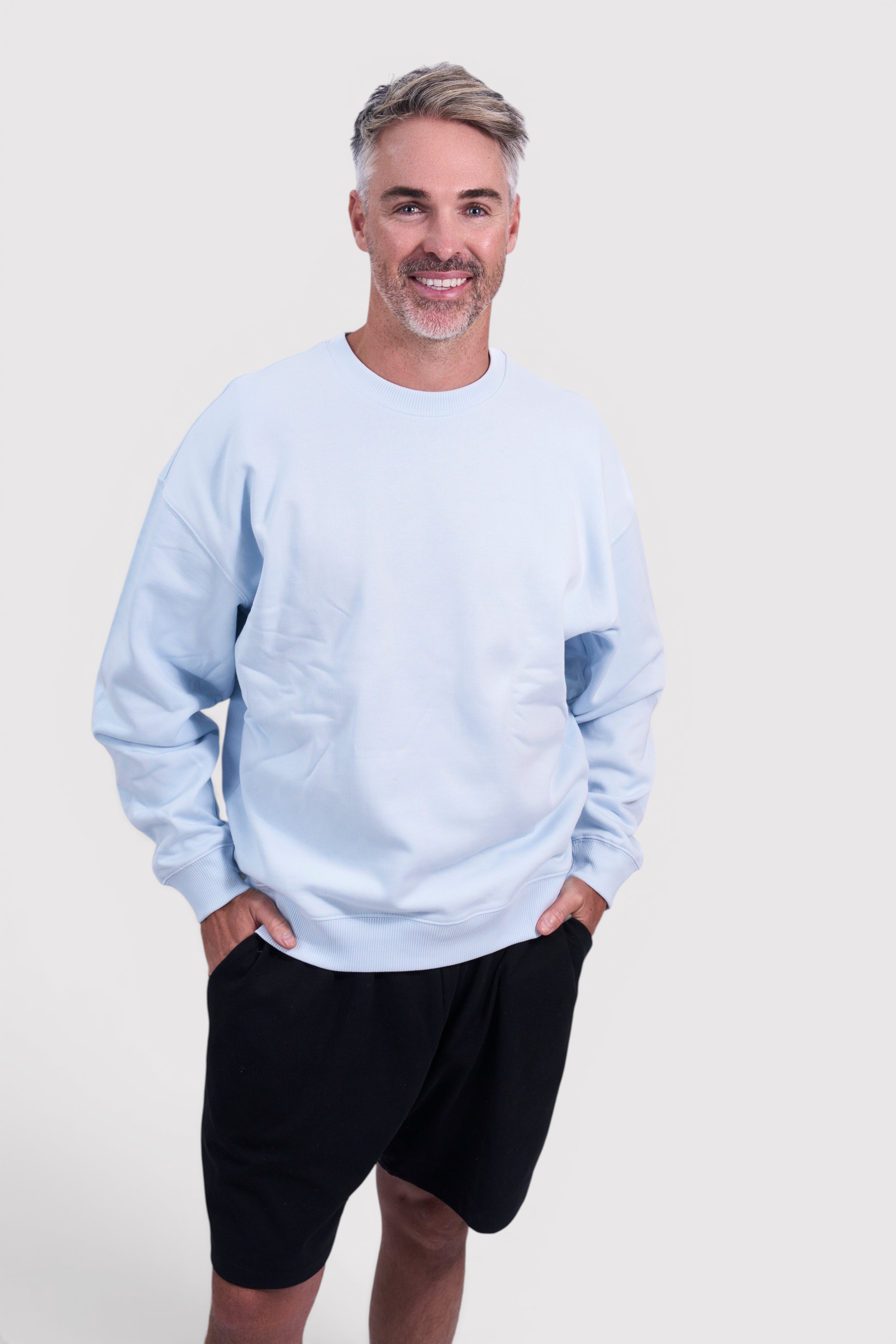 STAPLE Co light blue oversized crew neck jumper made from brushed organic cotton. Model wears black shorts.