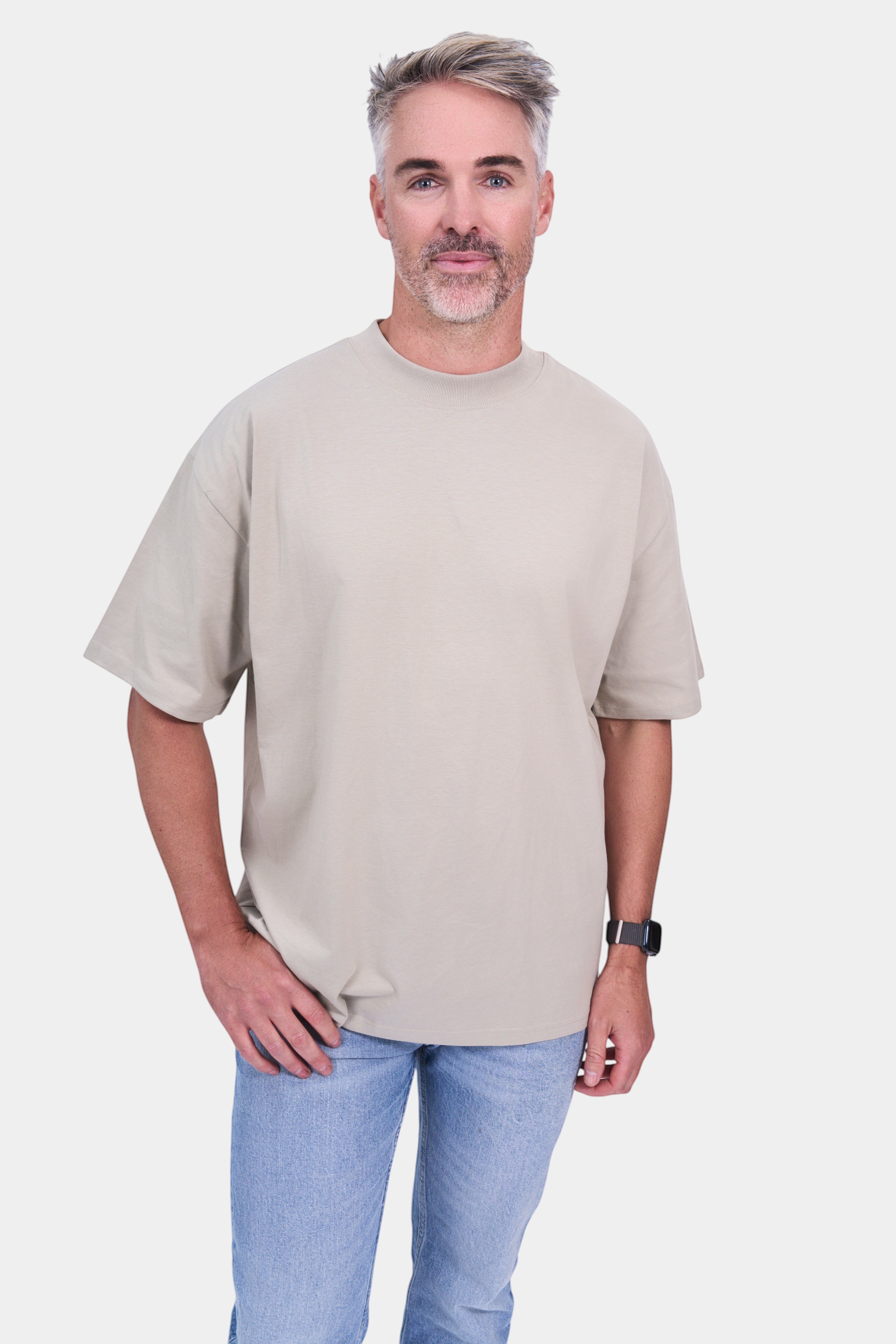 STAPLE Co. beige organic cotton oversized high neck t-shirt on a man with light wash jeans.