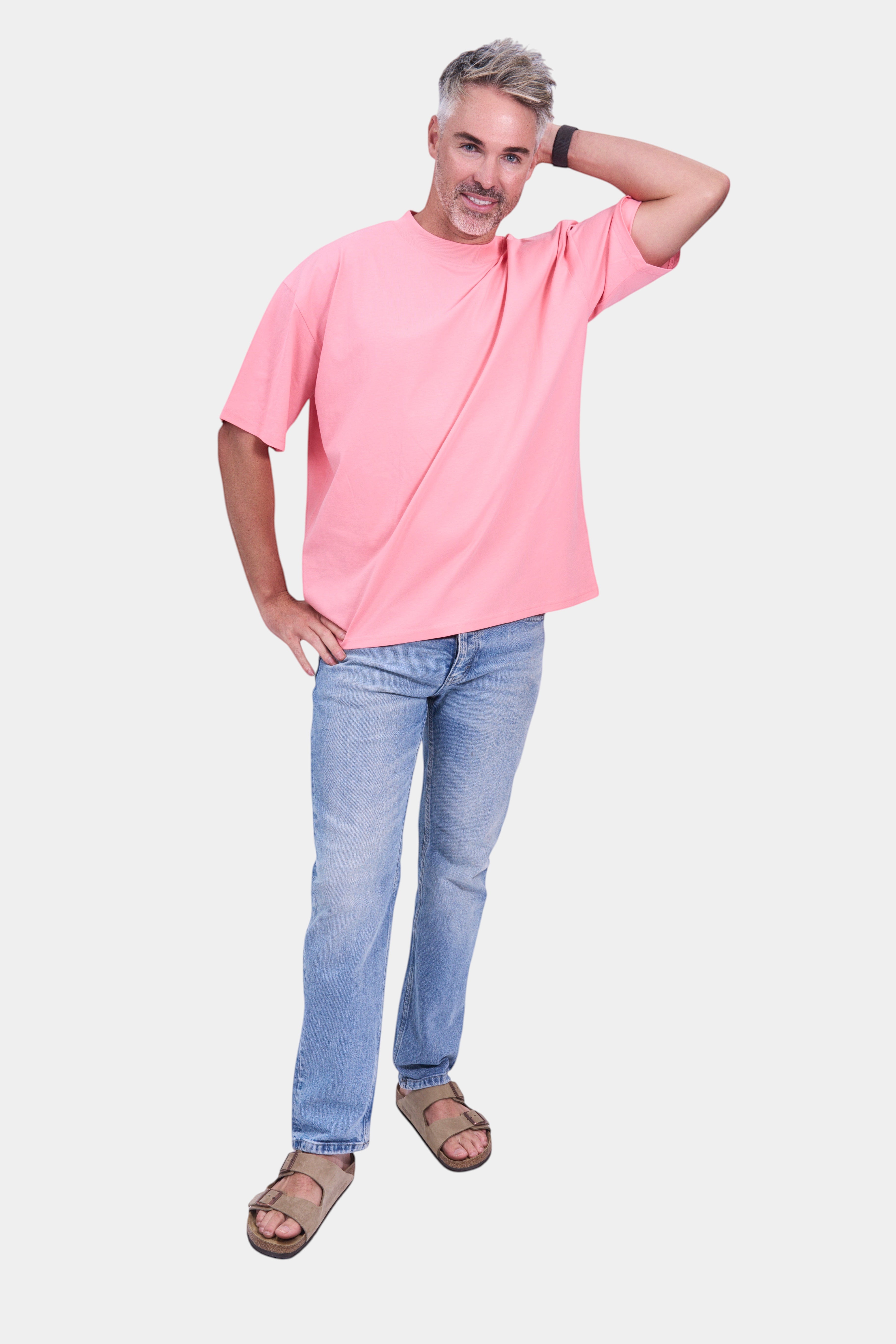 STAPLE Co pink organic cotton oversized high neck t-shirt on a man with light wash jeans and sandals.