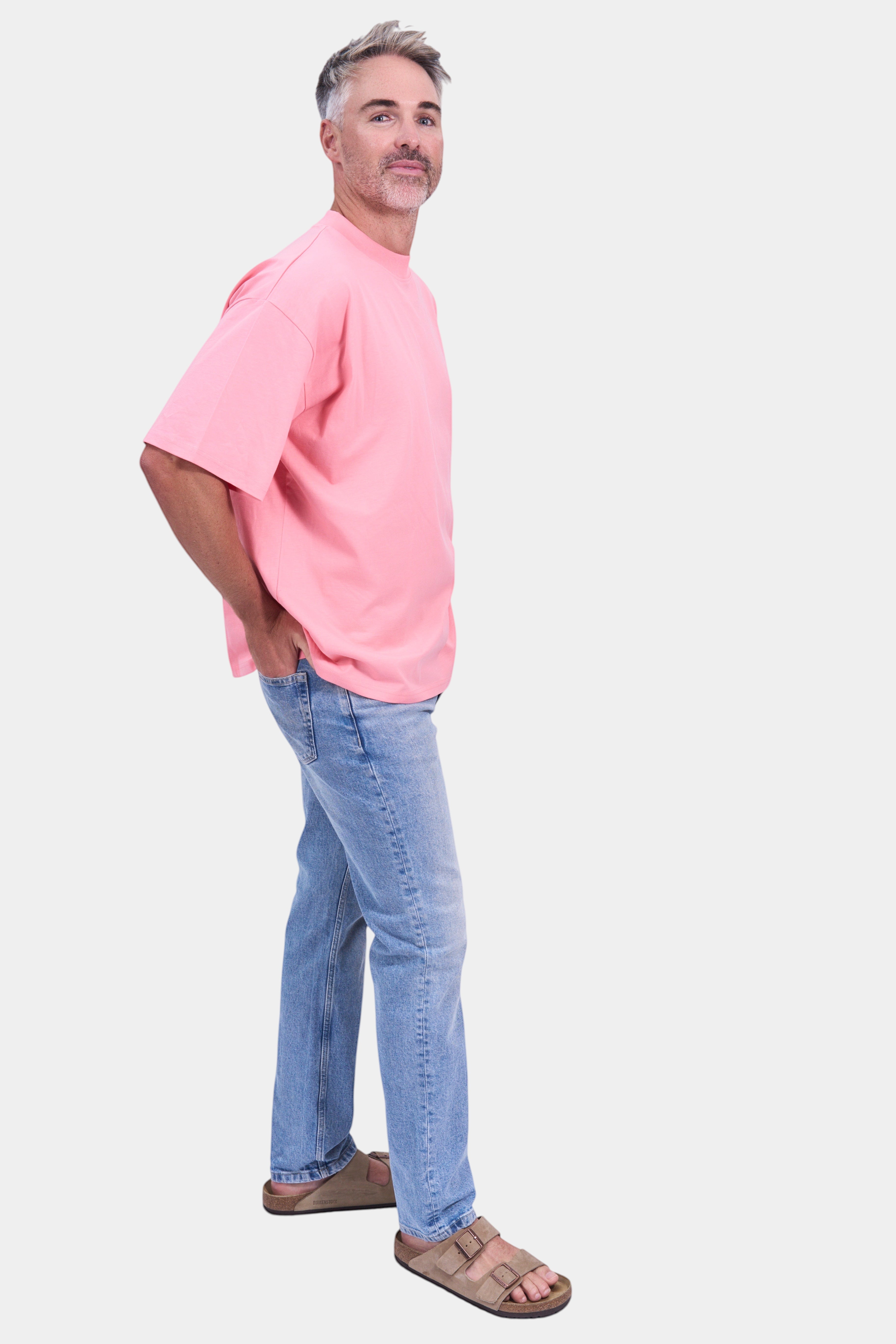 STAPLE Co. pink organic cotton oversized high neck t-shirt on a man with light wash jeans.