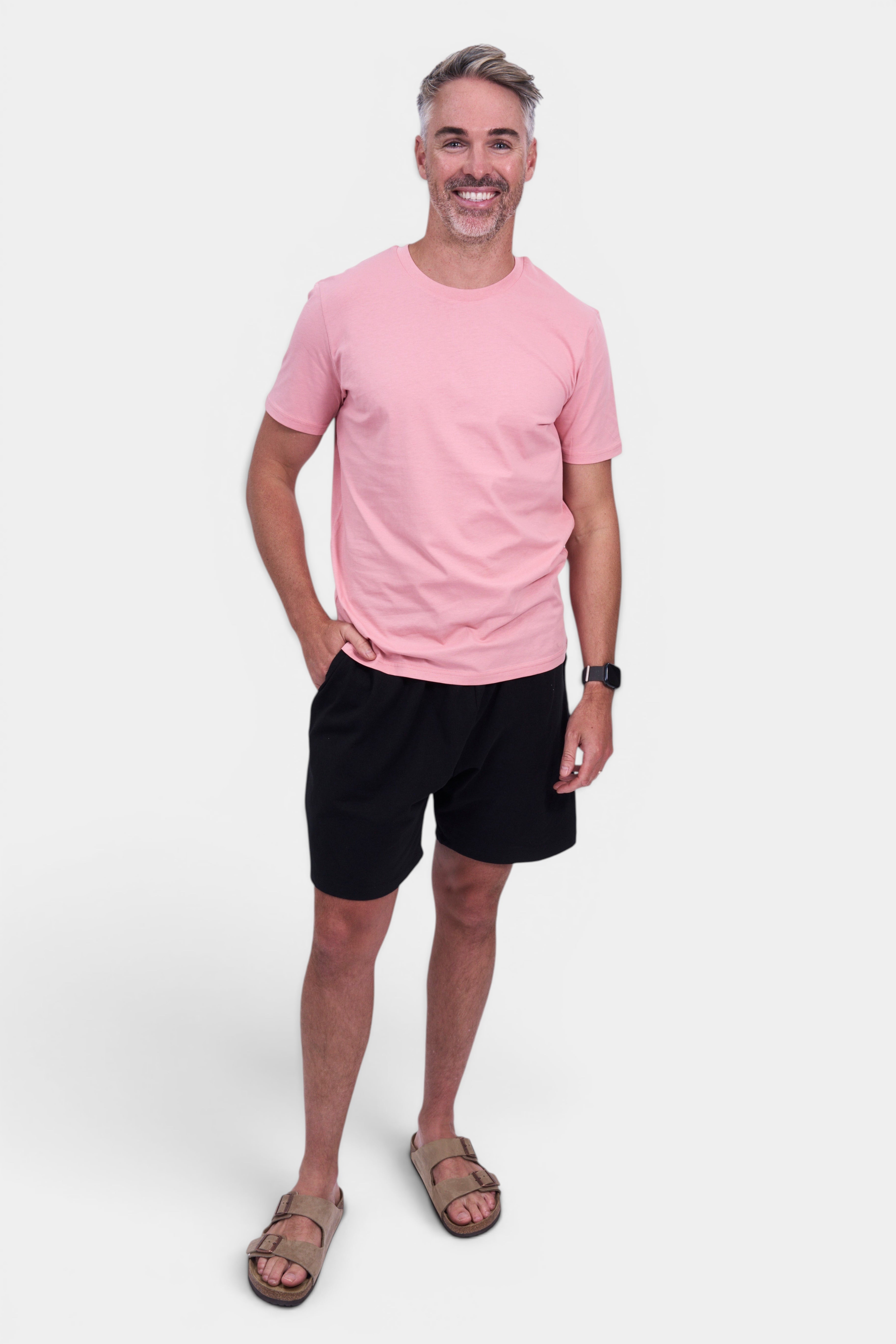 STAPLE Co. pink organic cotton classic fit tee on a man wearing black shorts and tan sandals.